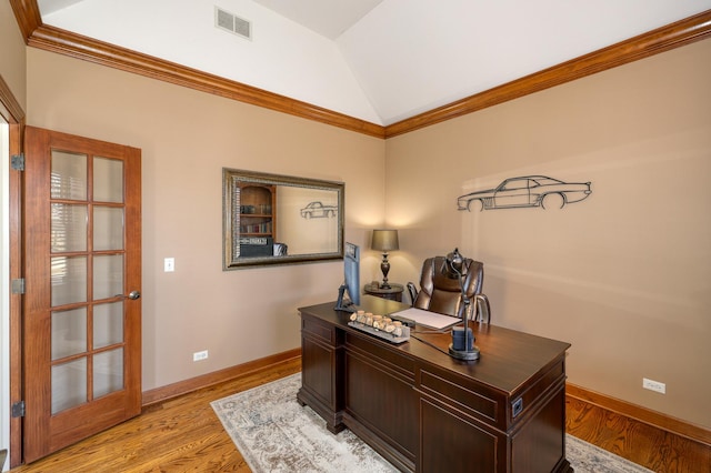 office space with visible vents, baseboards, lofted ceiling, ornamental molding, and light wood-style flooring