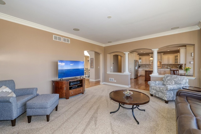 living area featuring arched walkways, visible vents, crown molding, and ornate columns