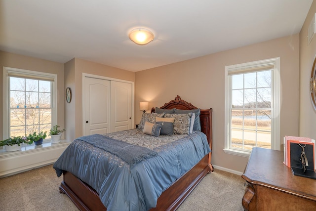 carpeted bedroom with a closet, multiple windows, and baseboards