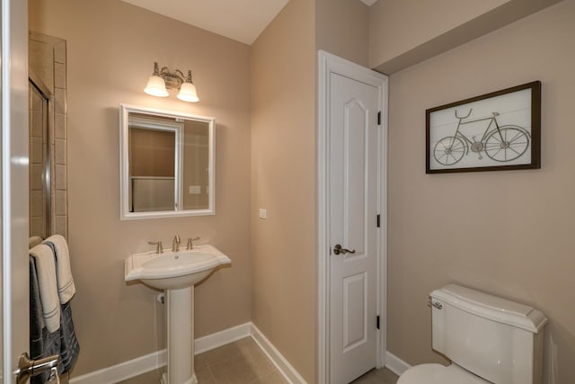 bathroom featuring tile patterned floors, toilet, baseboards, and a sink