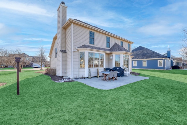 rear view of property featuring a yard, a chimney, and a patio area