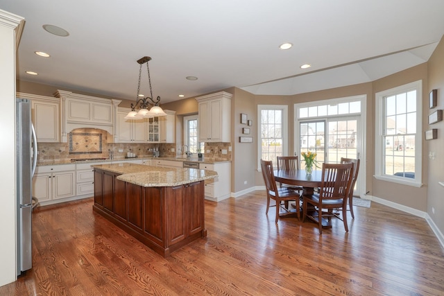 kitchen featuring tasteful backsplash, custom range hood, wood finished floors, stainless steel appliances, and a sink