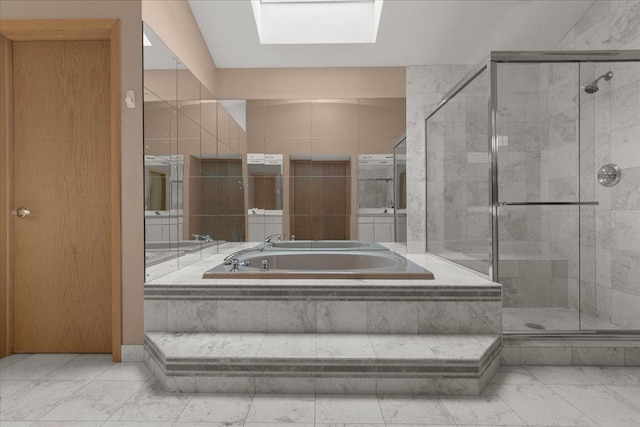 bathroom featuring a skylight, marble finish floor, a shower stall, and a bath