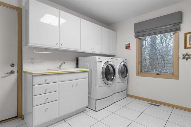 laundry room with cabinet space, baseboards, visible vents, washer and clothes dryer, and a sink