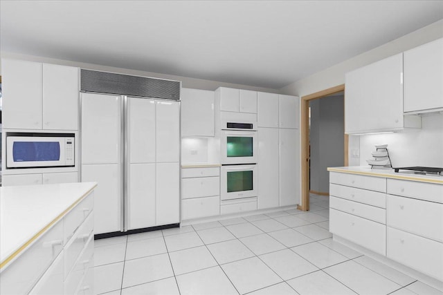 kitchen featuring white appliances, white cabinetry, light countertops, and light tile patterned flooring