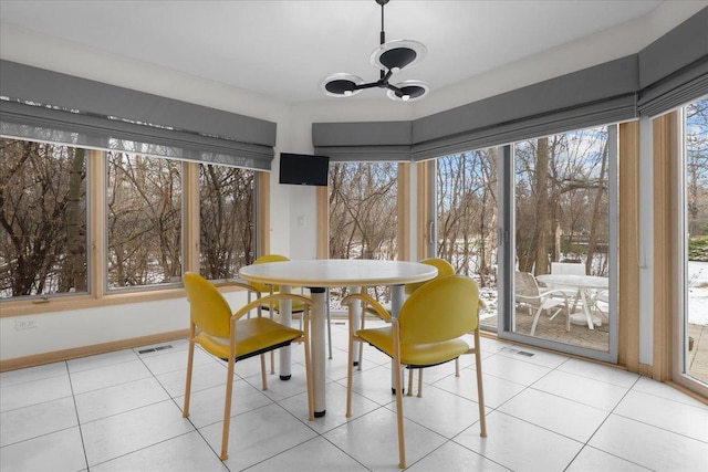 dining space with light tile patterned flooring, a notable chandelier, visible vents, and baseboards