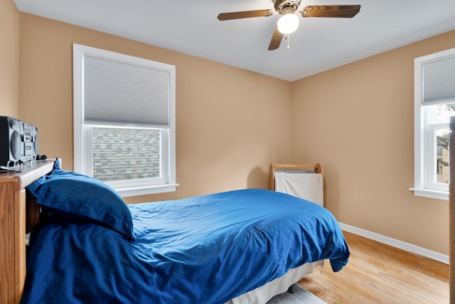 bedroom featuring ceiling fan, baseboards, and wood finished floors