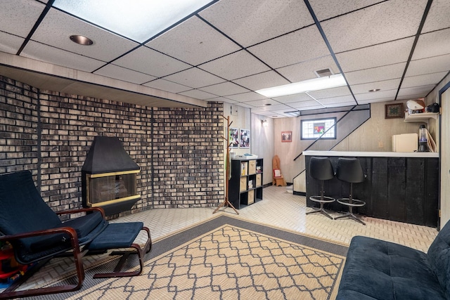 living area featuring carpet, visible vents, a drop ceiling, and a bar