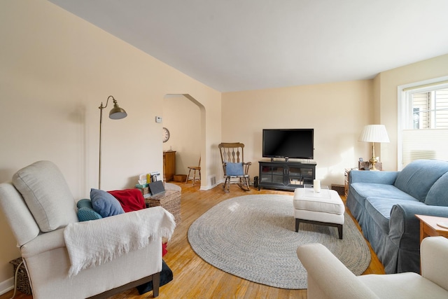 living room with light wood-type flooring and arched walkways