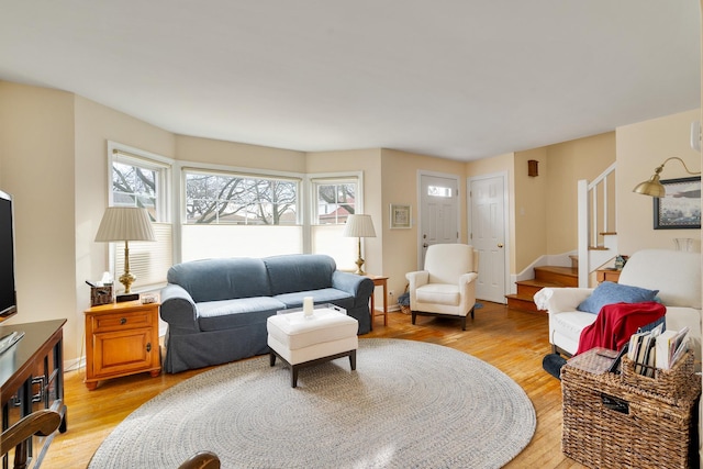 living room with light wood finished floors, stairs, and baseboards