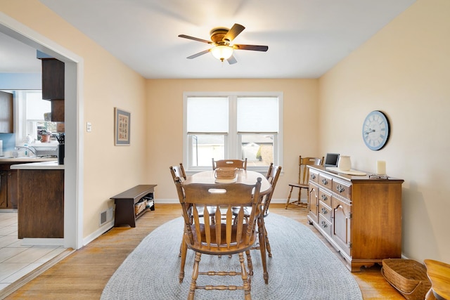 dining space featuring light wood finished floors, baseboards, a ceiling fan, and a wealth of natural light