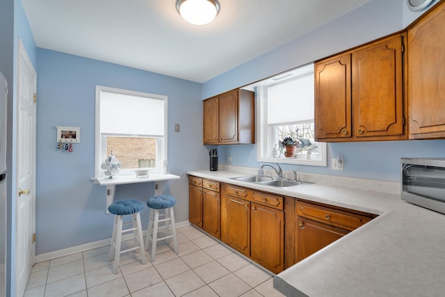 kitchen with light tile patterned floors, brown cabinets, and a sink