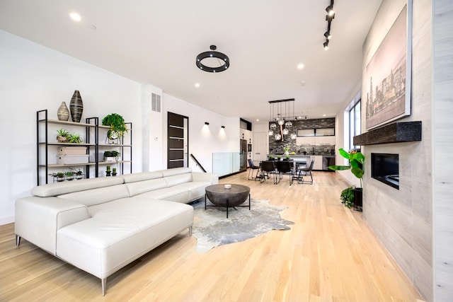 living area featuring recessed lighting, light wood-type flooring, visible vents, and rail lighting