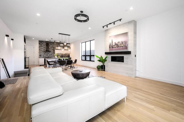 living room with recessed lighting, a fireplace, track lighting, and light wood finished floors