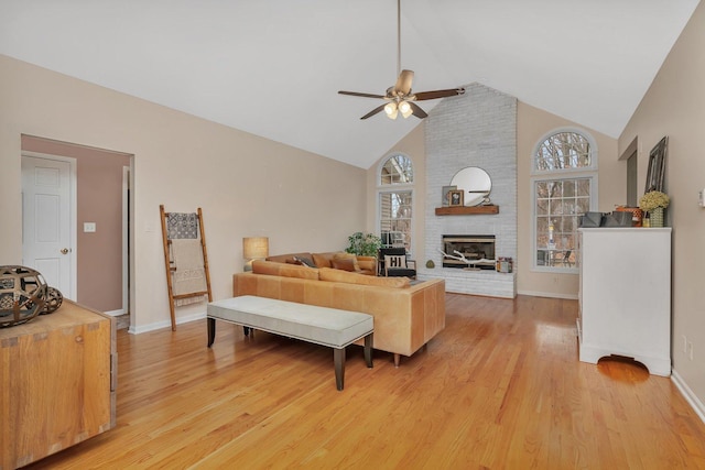 living room with a healthy amount of sunlight, a brick fireplace, and light wood-style flooring