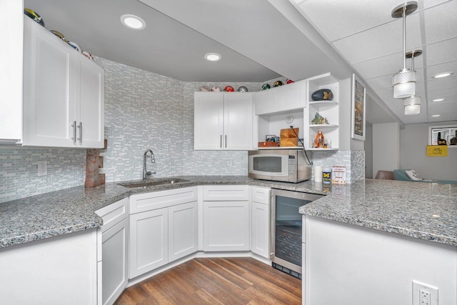 kitchen featuring dark wood-style floors, open shelves, white microwave, a sink, and beverage cooler