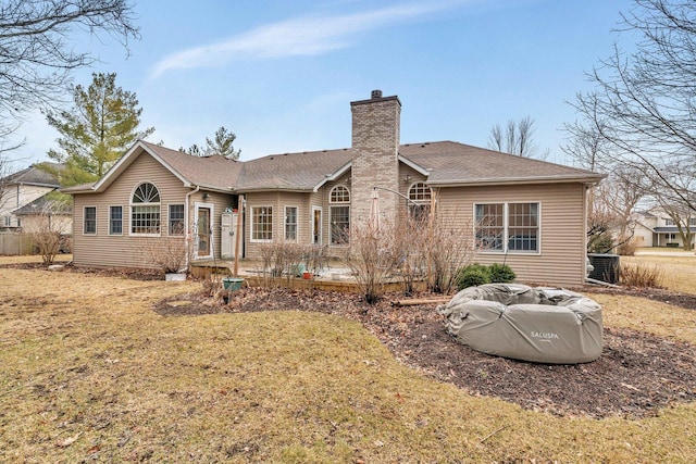 back of property with a shingled roof, a chimney, and a lawn