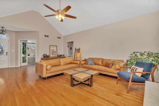 living area with high vaulted ceiling, visible vents, light wood finished floors, and a ceiling fan