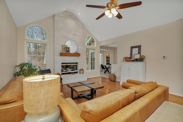 living room featuring baseboards, ceiling fan, wood finished floors, a fireplace, and high vaulted ceiling