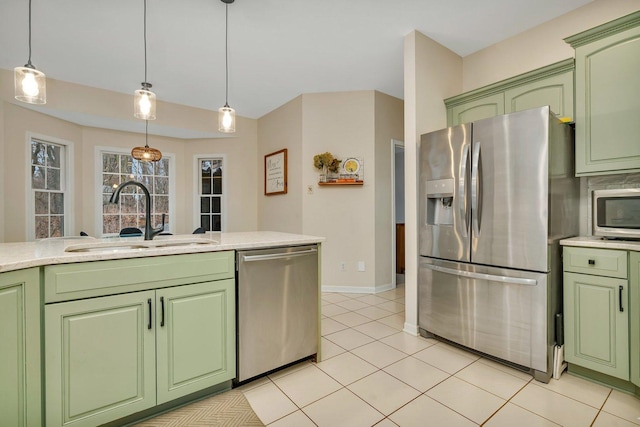 kitchen with a sink, appliances with stainless steel finishes, green cabinetry, and decorative light fixtures