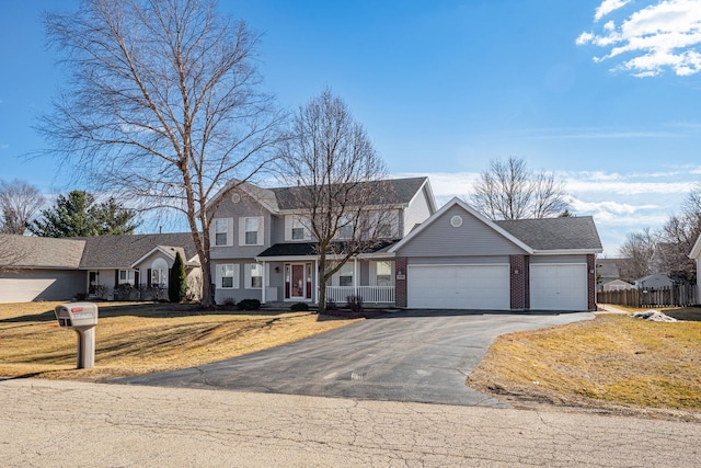 view of front of home featuring brick siding, an attached garage, a front yard, fence, and driveway