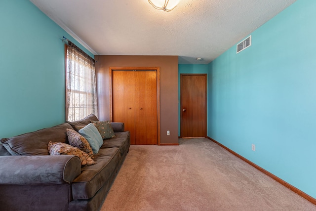 living area featuring light carpet, a textured ceiling, visible vents, and baseboards