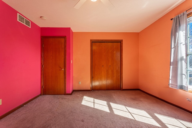 carpeted spare room featuring ceiling fan, visible vents, and baseboards