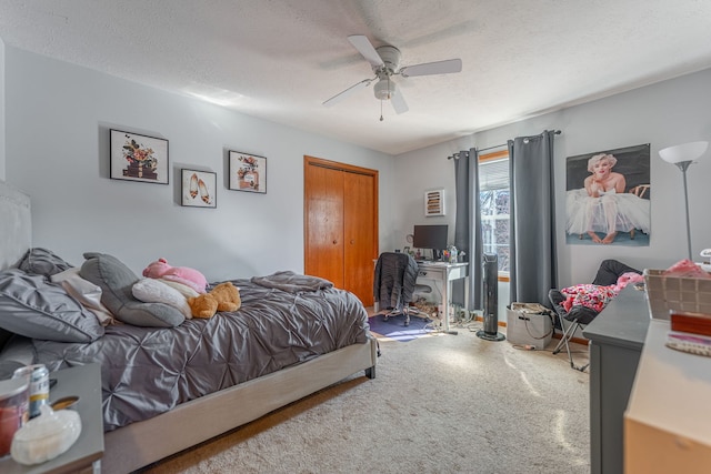 bedroom with a textured ceiling, carpet floors, a closet, and a ceiling fan