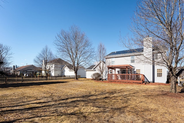 rear view of property featuring a yard, a chimney, fence, and a wooden deck