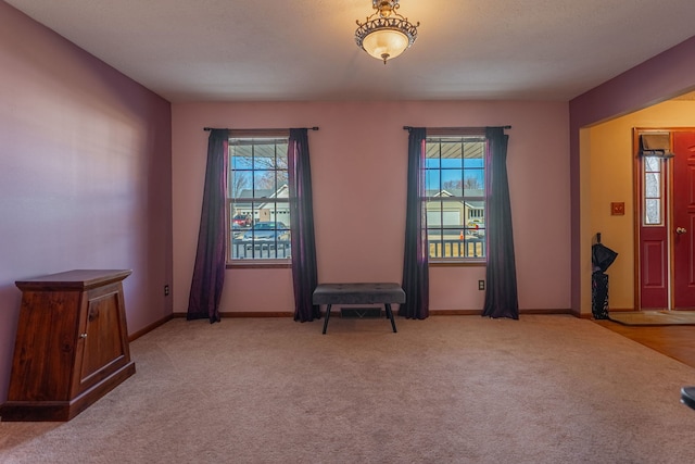 unfurnished room featuring light carpet and baseboards