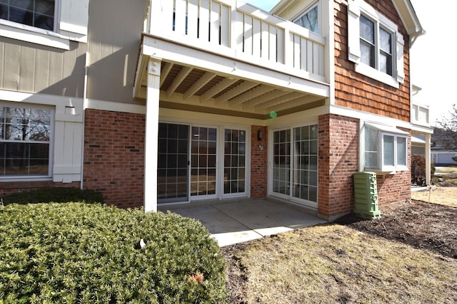 property entrance with a patio area, brick siding, and a balcony