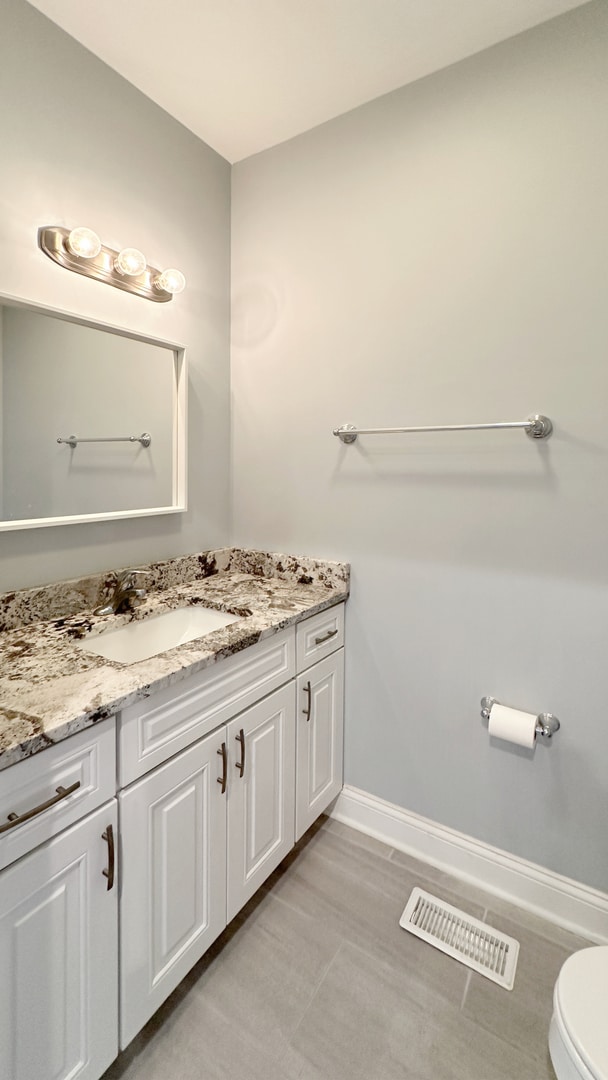 bathroom with toilet, vanity, visible vents, and baseboards