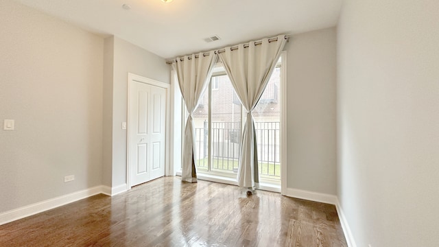 empty room featuring a healthy amount of sunlight, baseboards, and wood finished floors