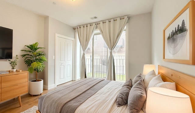 bedroom featuring baseboards, light wood finished floors, visible vents, and access to exterior