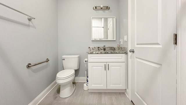 half bath with vanity, toilet, and baseboards