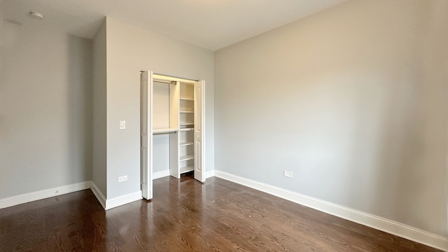 unfurnished bedroom featuring a closet, baseboards, and dark wood-style flooring