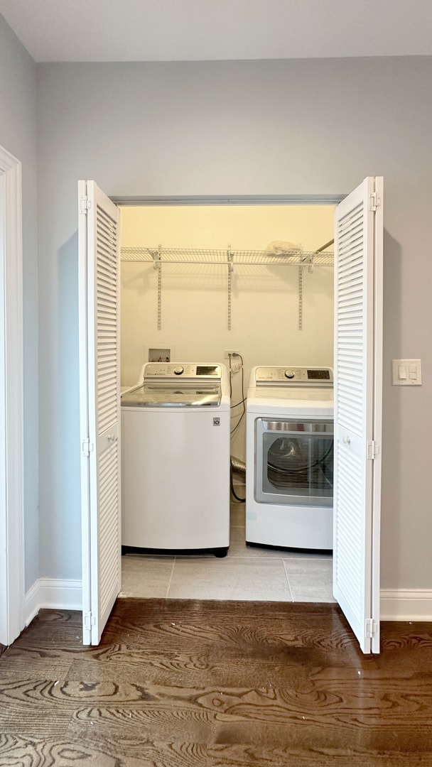 clothes washing area with light tile patterned floors, laundry area, separate washer and dryer, and baseboards