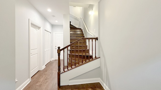 stairs with recessed lighting, wood finished floors, and baseboards