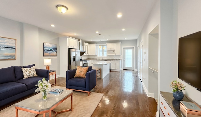 living area featuring baseboards, dark wood finished floors, and recessed lighting