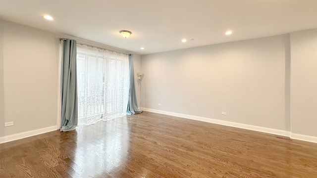 unfurnished room featuring recessed lighting, wood finished floors, and baseboards