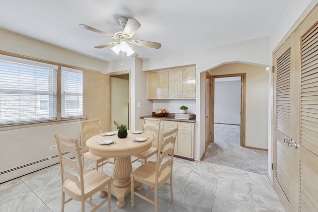 dining space featuring baseboards, arched walkways, a ceiling fan, light colored carpet, and a baseboard heating unit