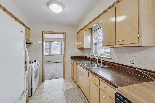 kitchen with white appliances, a sink, baseboard heating, backsplash, and dark countertops