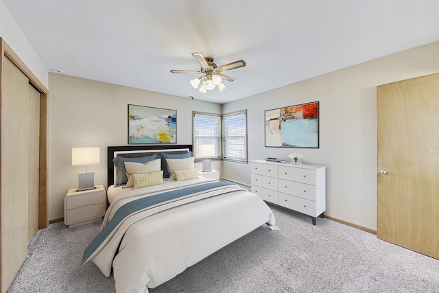 bedroom with ceiling fan, baseboards, a closet, and light colored carpet