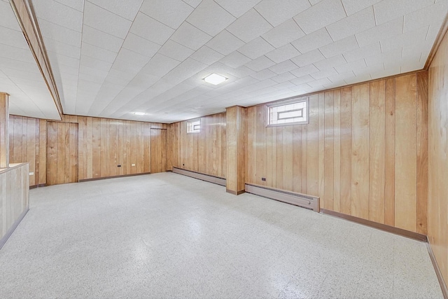 below grade area featuring baseboards, a baseboard radiator, tile patterned floors, wood walls, and a baseboard heating unit