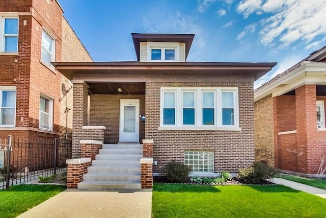 view of front of home with entry steps, fence, a front lawn, and brick siding