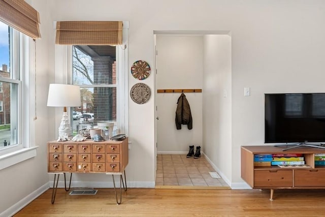 corridor featuring visible vents, baseboards, and wood finished floors