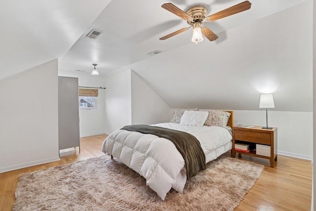 bedroom featuring visible vents, light wood finished floors, and lofted ceiling