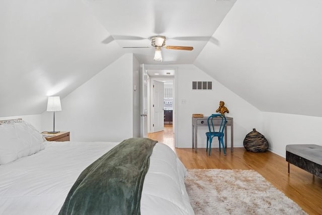 bedroom with a ceiling fan, visible vents, wood finished floors, lofted ceiling, and baseboards