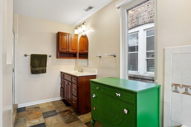 full bath with stone finish flooring, vanity, baseboards, and visible vents