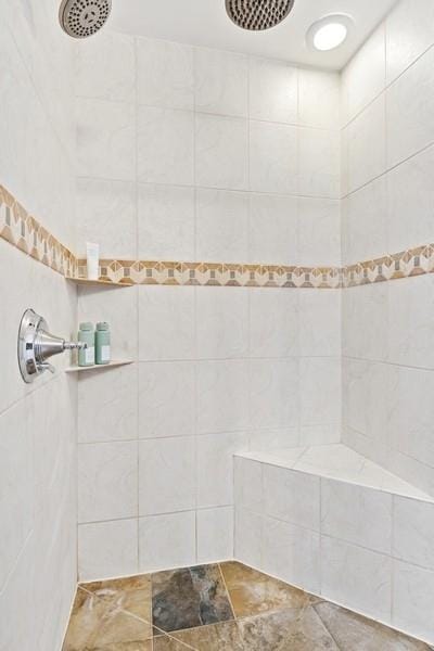 full bath featuring tiled shower and stone finish floor
